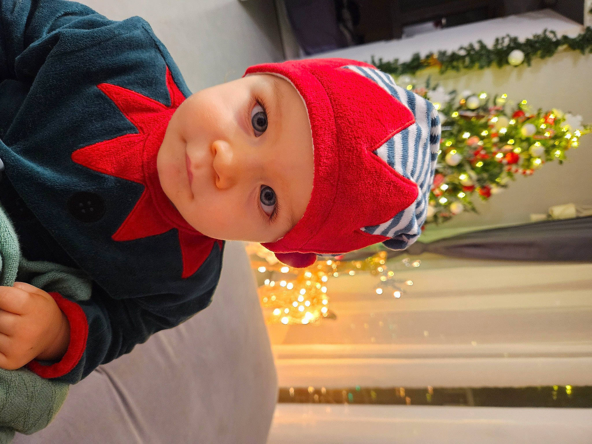 Enio participe au concours pour gagner de l'argent avec cette photo : cap, carmine, child, christmas, christmas_decoration, christmas_ornament, event, facial_expression, fun, happy, hat, headwear, holiday, person, plant, smile, standing, toddler, tradition, tree