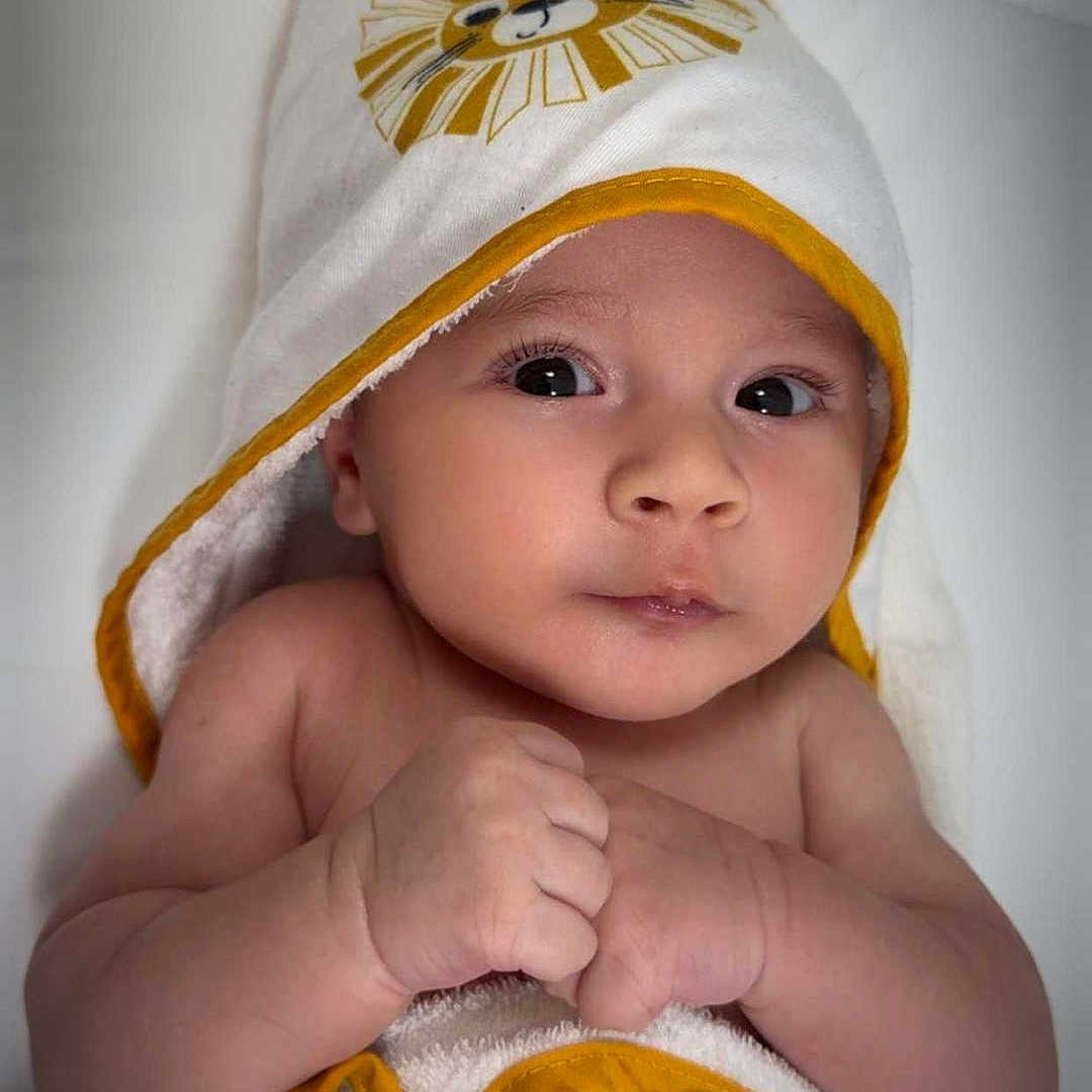 Liam a rejoint le concours — aidez-le/la à gagner de superbes lots ! baby, child, closeup, cute, expression, face, hands, hooded_towel, indoor, infant, lion_design, newborn, person, portrait, skin, soft, towel, white, wrapped, yellow