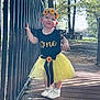 toddler, child, girl, yellow_tutu, black_shirt, sunflower, headband, outdoor, bridge, railing, trees, sunlight, shadow, smiling, white_shoes, grass, park, nature, cute, happy