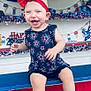 Hazel is registered to the contest to win money with this photo: baby, child, smiling, red_bow, headband, dress, stars, fireworks_pattern, bench, patriotic, holiday, 4th_of_july, decorations, happy, sitting, indoor, celebration, person, cute, festive