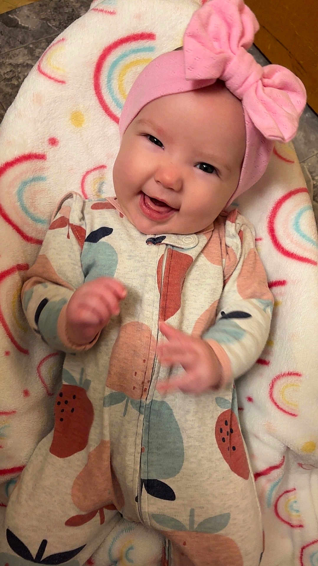 Harleigha joined the competition — help win amazing prizes! baby, infant, smile, headband, pink_bow, onesie, fruit_pattern, blanket, rainbow_pattern, happy, cute, lying_down, child, face, hand, cozy, indoors, soft_texture, apparel, playful