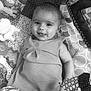 Enid participe au concours pour gagner de l'argent avec cette photo : baby, baby_dress, black_and_white, child, clothing, cute, fabric, face, happy, head, indoors, infant, lying_down, patterned_background, person, play_mat, portrait, smiling, soft_toys, toy
