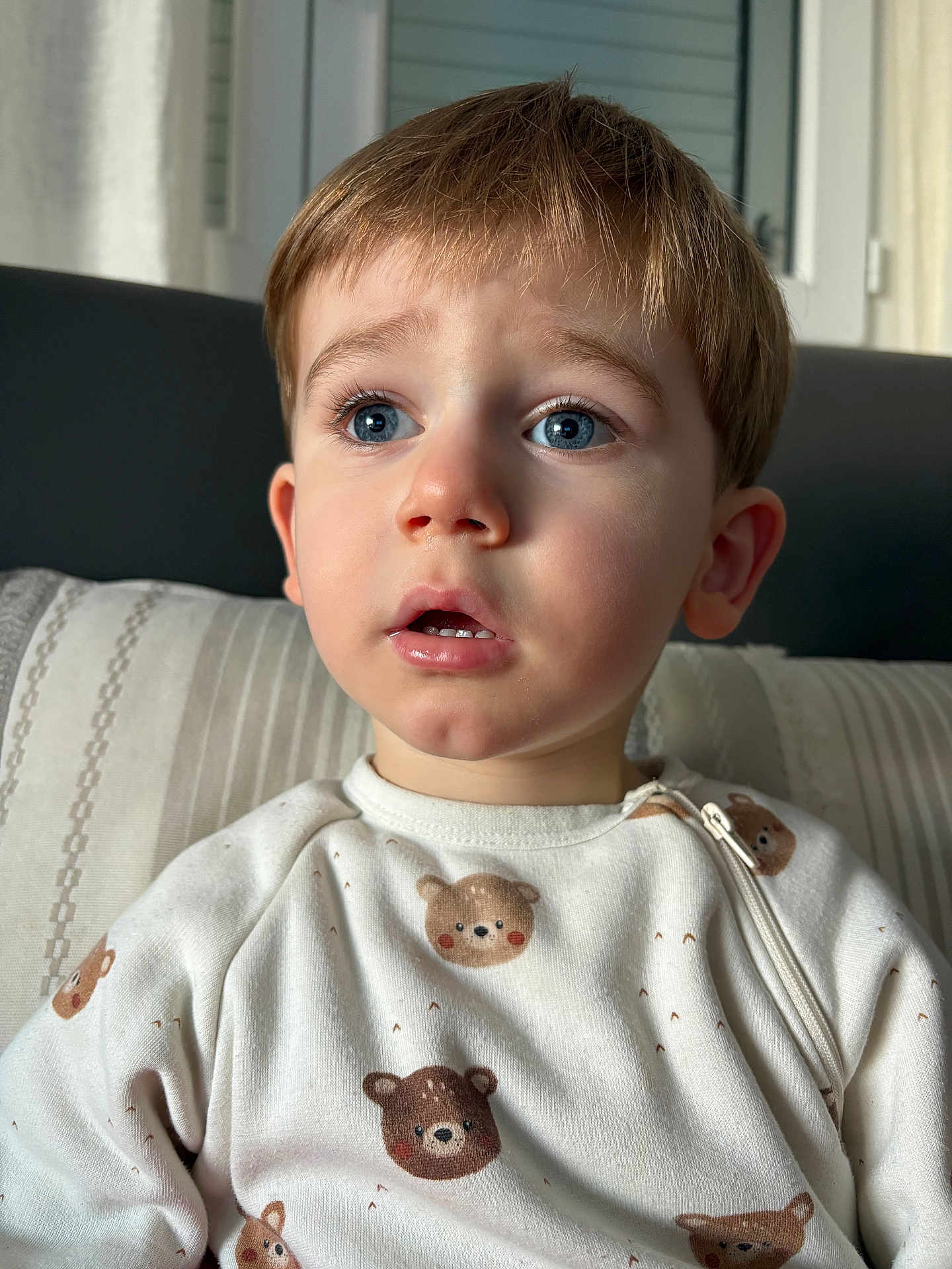 Marc Andria participe au concours pour gagner de l'argent avec cette photo : child, toddler, boy, face, blue_eyes, surprised_expression, short_hair, pajamas, bear_print, close_up, portrait, indoor, sofa, pillow, natural_light, window, skin, eyelashes, nose, mouth_open