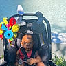 Saage joined the competition — help win amazing prizes! baby, child, colorful_toy, expression, grass, infant, nature, outdoor, park, person, playful, plaything, rocks, seat_belt, shadow, stroller, summer, sunlight, toy, water_fountain