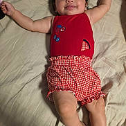 Violet joined the competition — help win amazing prizes! baby, child, smile, lying_down, red_clothing, checkered_shorts, bed, blanket, happy, infant, cute, person, skin, arm, leg, head, face, indoors, soft_lighting, comfortable