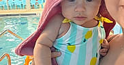 Violet is registered to the contest to win money with this photo: adult, baby, background, blue_chairs, child, colorful, cute, eyes, face, hand, holding, indoor, person, photography, pool, reflection, swimsuit, towel, water, yellow_wall