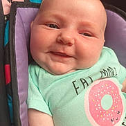 Elena is registered to the contest to win money with this photo: baby, cheeks, child, closeup, clothing, cute, donut_graphic, eyes, fabric, face, happy, indoors, infant, mint_green, patterned_background, portrait, seated, smiling, soft_lighting, tshirt