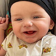 Isaac participe au concours pour gagner de l'argent avec cette photo : baby, infant, smiling, face, headwear, hat, onesie, winnie_the_pooh, hand, arm, pillow, bedding, cheeks, blue_eyes, tooth, mouth, portrait, closeup, happy, skin