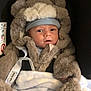Noble joined the competition — help win amazing prizes! baby, infant, car_seat, blanket, fur_clothing, hat, face, cute, child, warm_clothing, bundle, indoors, seat, soft_texture, cozy, person, winter_wear, hood, glove, fur