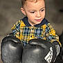child, boy, boxing_gloves, adidas, plaid_shirt, yellow, green, indoor, curious, playful, clothing, person, young, cute, portrait, short_hair, casual, jeans, focused, gloves
