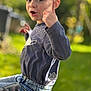 child, boy, pointing, outdoor, toy, truck, blue_shirt, jeans, garden, sunlight, greenery, expression, gesture, playful, portrait, smiling, daylight, casual_clothing, young, happy