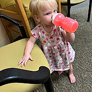 Ella joined the competition — help win amazing prizes! toddler, child, drinking, sippy_cup, blonde_hair, heart_pattern, dress, barefoot, carpet, chair, indoor, person, furniture, hand, floor, young_child, cute, standing, support, casual