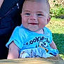 Royce is registered to the contest to win money with this photo: baby, child, smiling, blue_shirt, outdoor, sunlight, grass, wooden_table, face, person, happy, young_child, short_hair, cute, playful, daylight, toddler, clothing, jacket, nature
