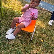 Deyana a rejoint le concours — aidez-le/la à gagner de superbes lots ! child, outdoor, grass, chair, playground, smiling, pink_clothing, sneakers, happy, fence, shorts, toddler, person, daylight, nature, seat, play_area, casual, young_child, snack