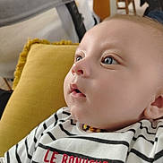 Gaël participe au concours pour gagner de l'argent avec cette photo : baby, beaded_necklace, blue_eyes, child, close_up, cozy, curious_expression, face, furniture, head, indoor, infant, person, portrait, sitting, skin, soft_lighting, striped_shirt, text_on_clothing, yellow_cushion