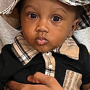 Jiaie is registered to the contest to win money with this photo: baby, bucket_hat, child, clothing, collar, curious, cute, eyes, face, hand, hat, holding, indoor, person, plaid, portrait, shirt, skin, tattoo, toddler