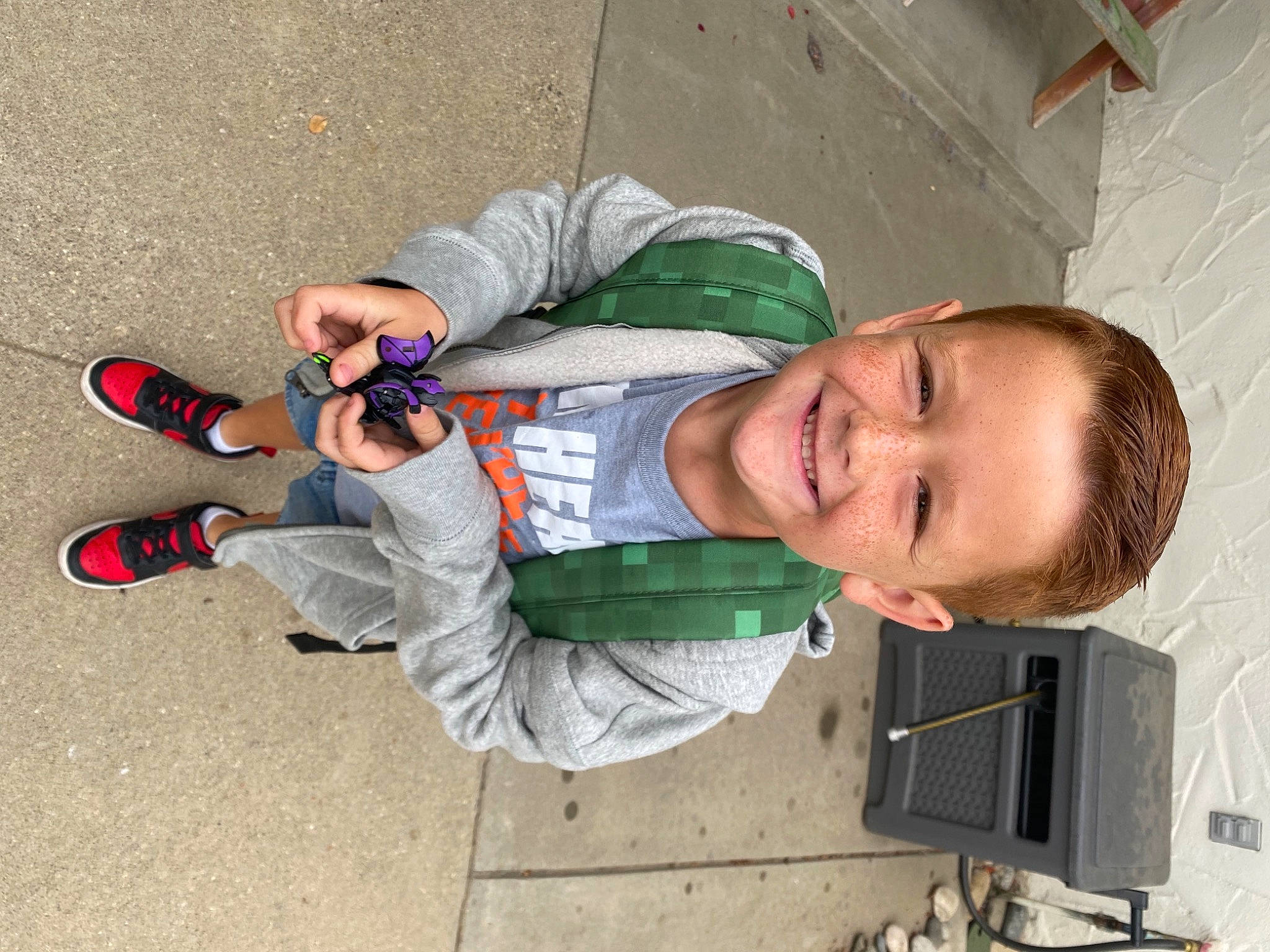 Bo is registered to the contest to win money with this photo: carmine, child, clothing, concrete, foot, fun, human_leg, joy, outdoor_shoe, person, recreation, sitting, smile, sneakers, toddler, walking_shoe