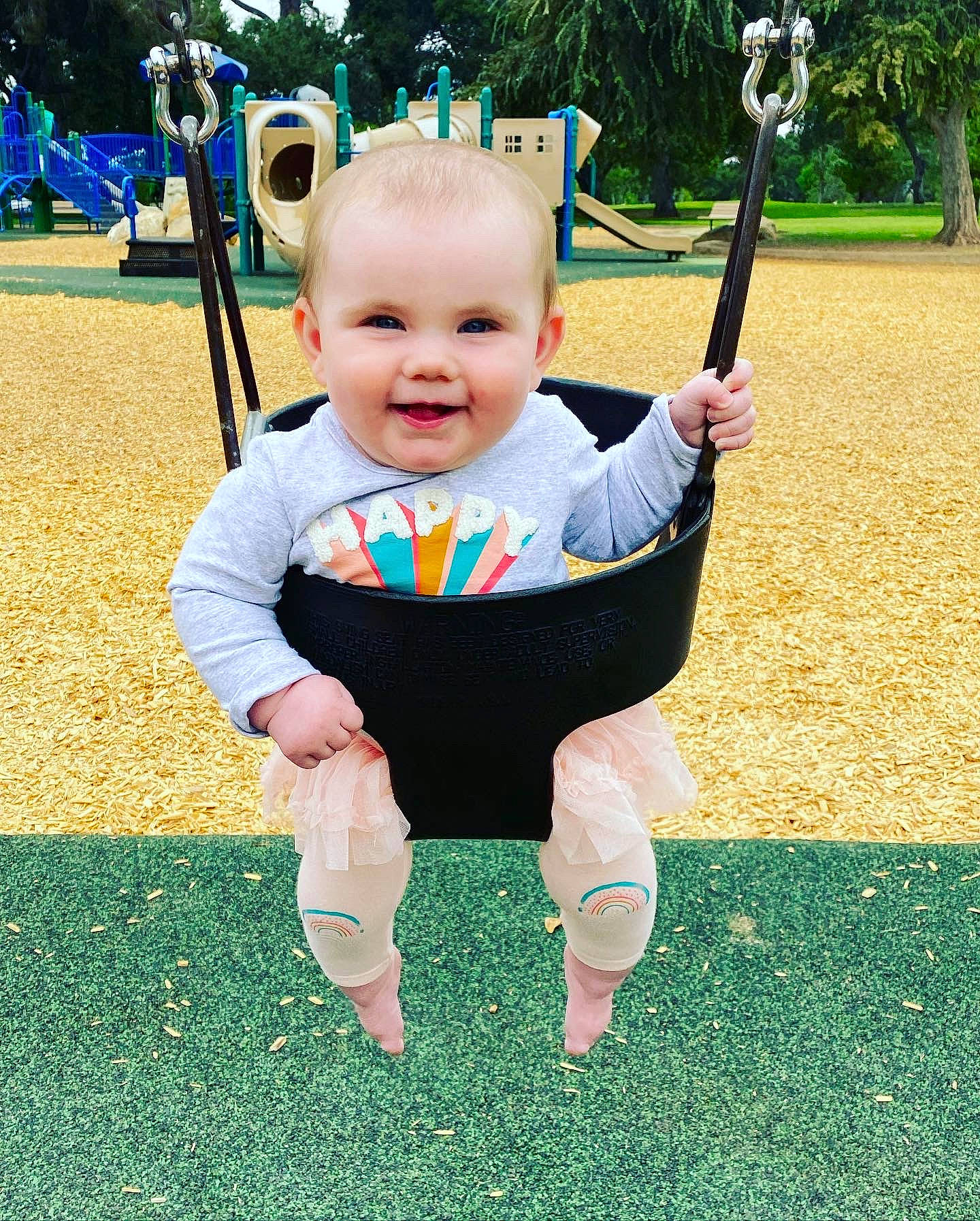 Bonnie is registered to the contest to win money with this photo: baby, baby_toddler_clothing, eye, face, grass, happy, head, human_body, joy, leisure, people_in_nature, person, plant, playground, recreation, sleeve, smile, standing, swing, t_shirt