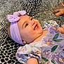 Ishtar is registered to the contest to win money with this photo: baby, child, smiling, headband, bow, floral_dress, blanket, leopard_print, tattoo, hand, skin, happy, cute, infant, portrait, lying_down, indoors, person, young_child, apparel