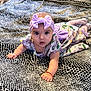 baby, infant, purple_headband, floral_dress, blanket, patterned_blanket, indoor, child, cute, lying_down, wide_eyes, open_mouth, curious, soft_lighting, toddler, crawling_position, bracelet, skin, person, portrait