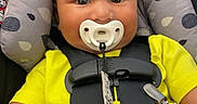 Zade is registered to the contest to win money with this photo: baby, black_shorts, car_seat, child, clothing, cute, face, headrest, indoor, infant, pacifier, patterned, person, portrait, safety_harness, seatbelt, sitting, smiling, yellow_shirt, young_child