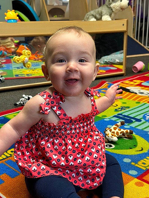 Victoria is registered to the contest to win money with this photo: baby, baby_toddler_clothing, chair, cheek, child, event, flooring, fun, happy, leisure, pattern, person, photograph, play, room, sitting, skin, smile, standing, toddler