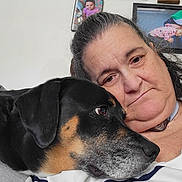 Ella is registered to the contest to win money with this photo: adult, affection, black_dog, close_up, companion, couch, cozy, dog, family_photos, framed_photo, indoor, living_room, pet, portrait, relaxed, selfie, senior_person, striped_shirt, tan_markings, woman