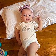 Sarah Esther joined the competition — help win amazing prizes! baby, infant, headband, onesie, elephant_print, pillow, wooden_floor, toy, colorful_toys, floor, face, person, cute, child, indoor, laying_down, smile, hand, foot, clothing