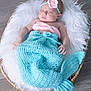 Khloe joined the competition — help win amazing prizes! baby, sleeping, mermaid_tail, knitted, headband, pink, turquoise, basket, fur, cozy, cute, infant, floor, wooden_floor, soft_texture, peaceful, portrait, indoors, resting, child