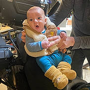 Giulio a rejoint le concours — aidez-le/la à gagner de superbes lots ! adult, baby, blue_pants, boots, child, clothing, cute, expression, footwear, hand, holding, indoor, motorcycle, person, seat, surprised, toolbox, vest, warm_clothing, workshop