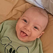 Giulio a rejoint le concours — aidez-le/la à gagner de superbes lots ! baby, smiling, tongue_out, green_shirt, cartoon_print, lying_down, bed, bedding, happy, infant, cute, child, face, skin, head, eyes, mouth, clothing, indoors, portrait