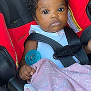 Zuri is registered to the contest to win money with this photo: baby, black, blanket, buckled, car_seat, child, close_up, curly_hair, indoor, infant, pacifier, photograph, pink_blanket, portrait, red, safe_travel, seatbelt, sitting, vehicle, wide_eyed
