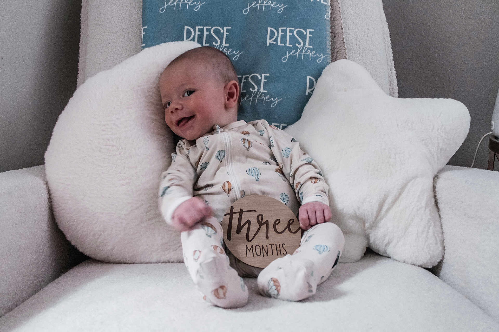 Reese joined the competition — help win amazing prizes! baby, infant, smile, onesie, pillow, star_pillow, cloud_pillow, chair, fluffy, cozy, indoor, child, cute, happy, person, newborn, sitting, wooden_sign, three_months, relaxing