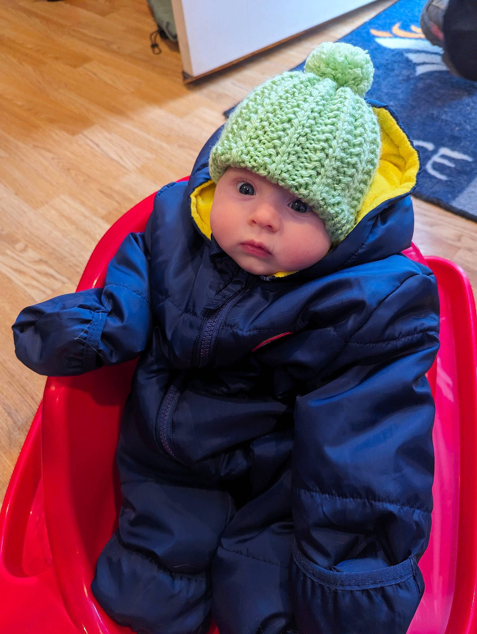 Ainsley is registered to the contest to win money with this photo: baby, baby_carriage, baby_products, baby_toddler_clothing, beanie, cap, comfort, electric_blue, flooring, fun, hardwood, headgear, headwear, knit_cap, leisure, person, personal_protective_equipment, sitting, toddler, varnish