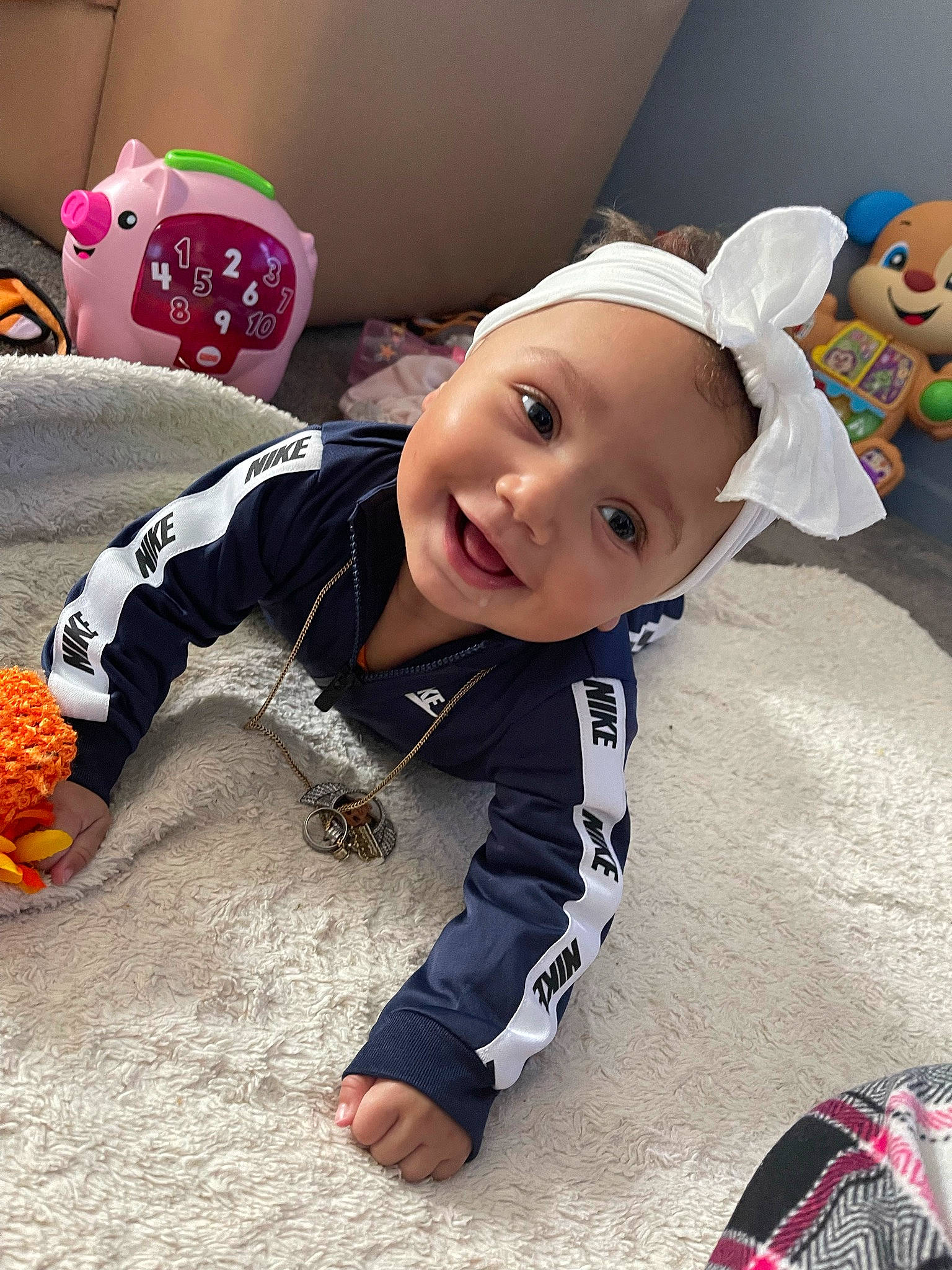 Genesis is registered to the contest to win money with this photo: baby, baby_toddler_clothing, calabaza, cap, carmine, child, eye, fashion_accessory, fictional_character, flooring, fun, fur, happy, head, joy, pattern, person, play, room, sitting