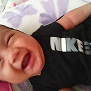 Miracle-Bloom joined the competition — help win amazing prizes! baby, black_shirt, blanket, child, close_up, clothing, cute, face, happy, indoor, infant, joyful, lying_down, pattern, person, smiling, soft_texture, text_on_clothing, toddler, young