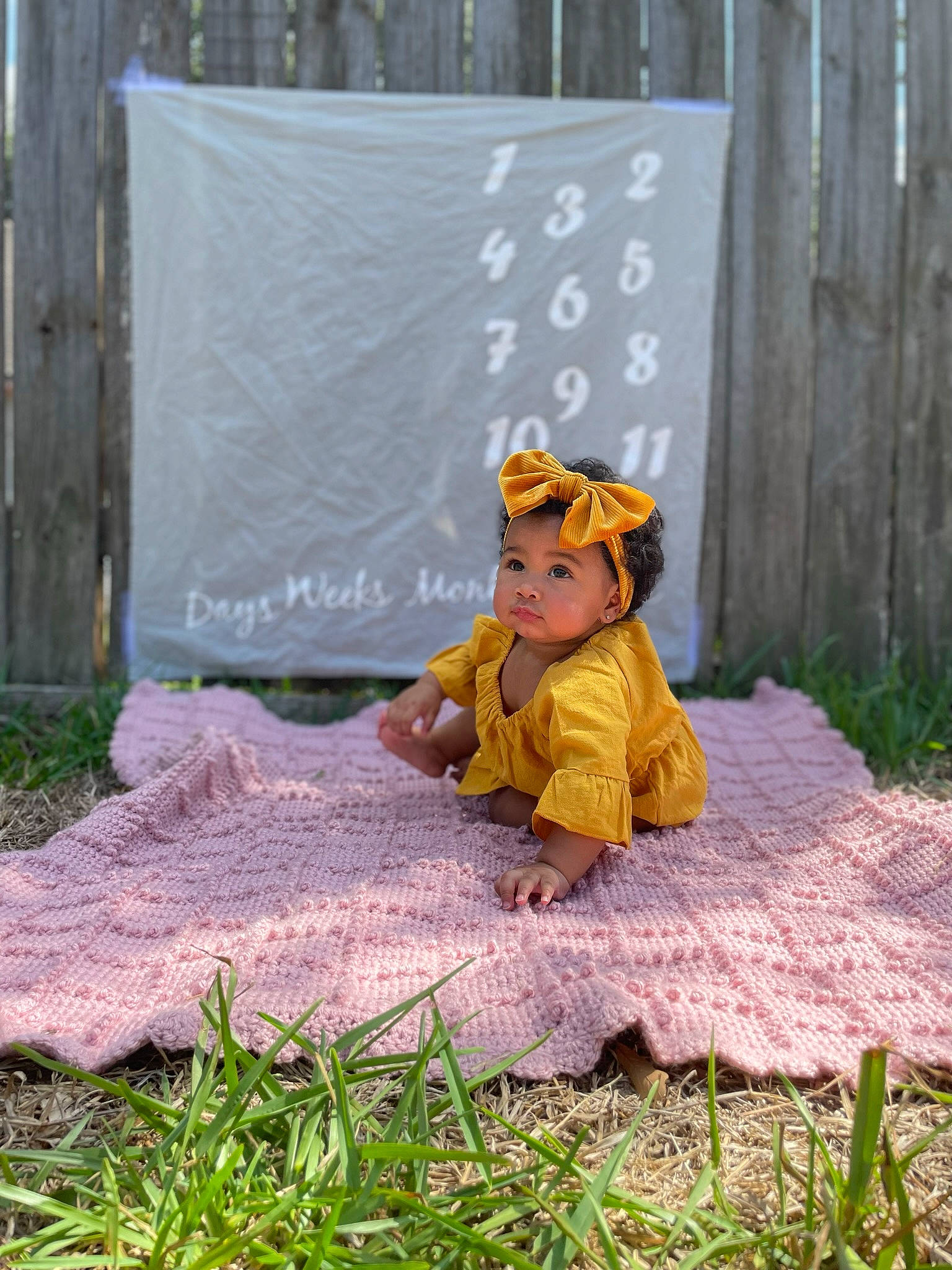 Alianna is registered to the contest to win money with this photo: adaptation, baby, child, deciduous, garden, grass, groundcover, hat, headwear, landscape, lawn, lawn_ornament, leaf, leisure, people_in_nature, person, plant, sitting, toddler, tree