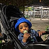 Dwane is registered to the contest to win money with this photo: toddler, child, stroller, pacifier, blue_hat, denim_jacket, night, urban, park, scaffolding, curious, outdoor, person, baby, seat, hand, face, small_child, clothing, expression