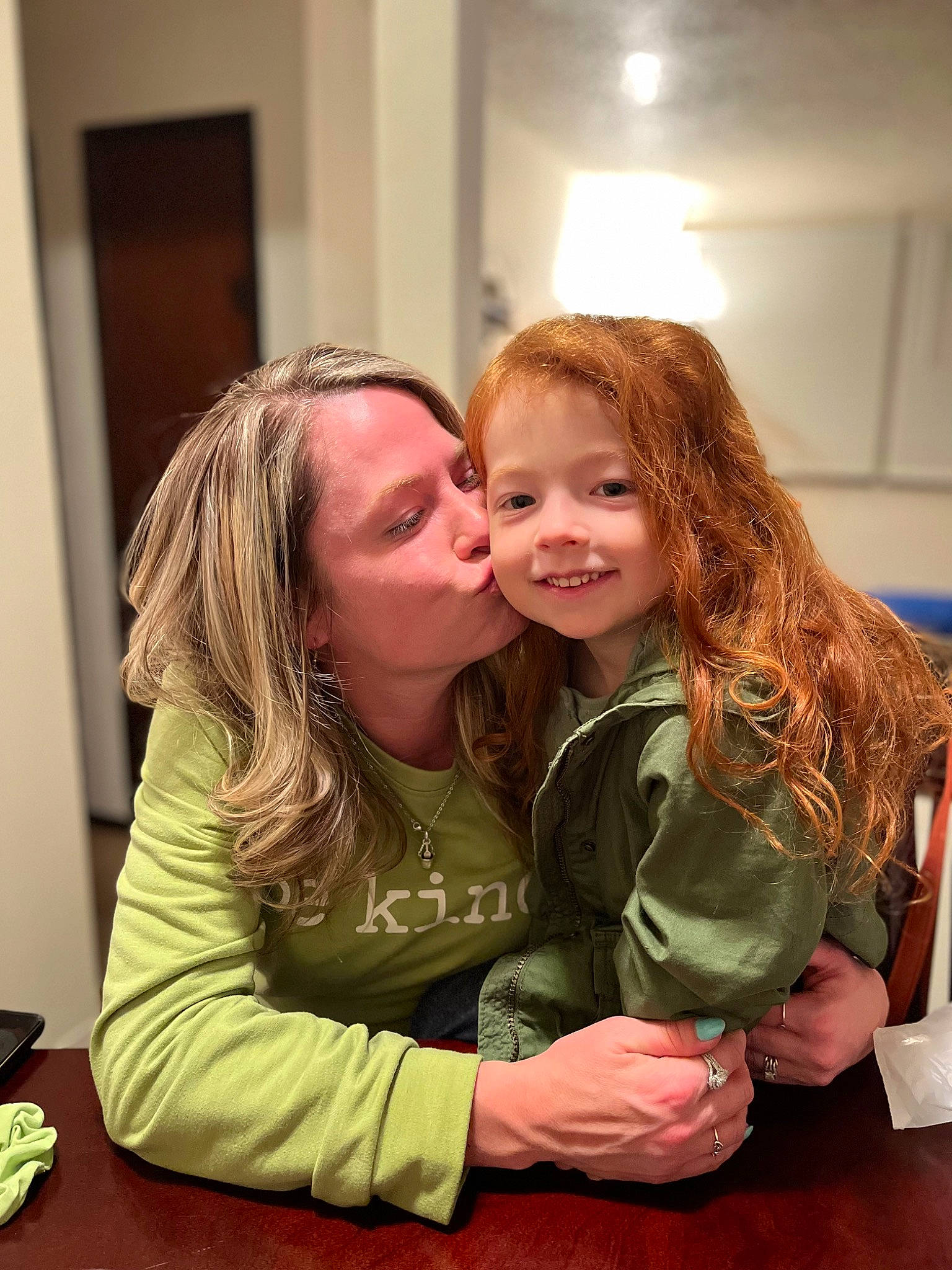 Maggie is registered to the contest to win money with this photo: blond, brown_hair, cheek, child, conversation, event, flooring, fun, gesture, happy, hug, iris, joy, kiss, laugh, long_hair, person, shoulder, sitting, smile