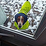 dog, snow, raincoat, yellow_clothing, blue_hood, wooden_deck, outdoor, pet, canine, looking_up, winter, cold_weather, door, glass, animal, fur, paw, tail, weather, coat