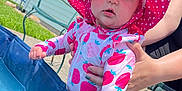 Audrey joined the competition — help win amazing prizes! baby, child, swimsuit, hat, pink, polka_dot, strawberry_pattern, pool, water, summer, outdoor, sunny, grass, house, adult_hand, curious, daylight, backyard, person, footwear