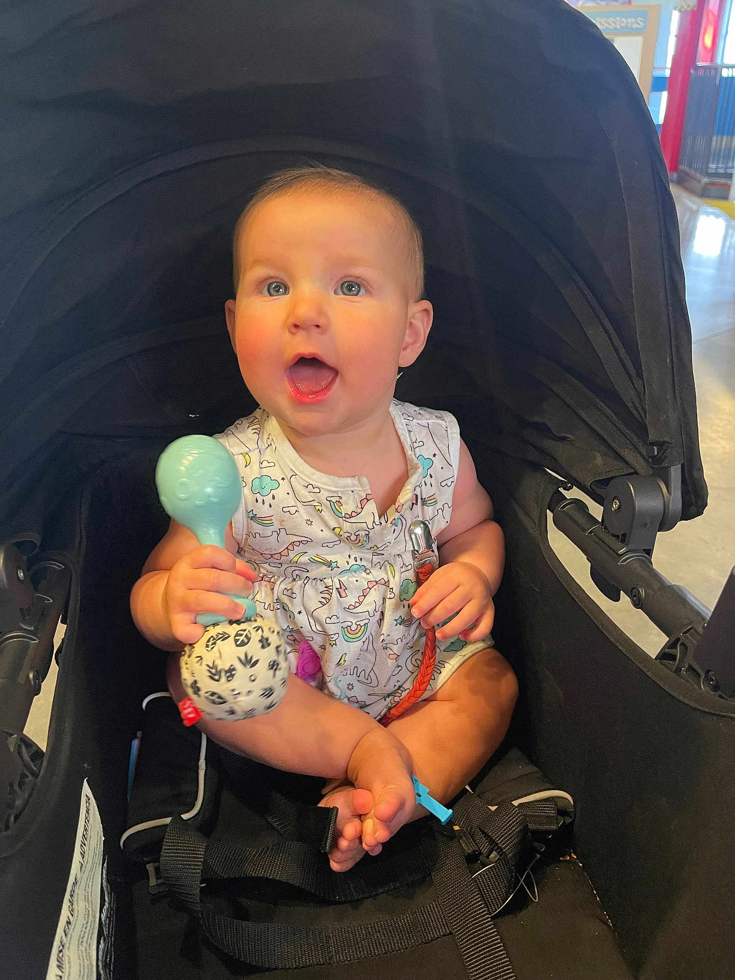 Audrey joined the competition — help win amazing prizes! baby, stroller, toy, indoor, child, expression, face, clothing, seatbelt, foot, hand, person, infant, colorful, plastic, fabric, happy, cute, sitting, closeup