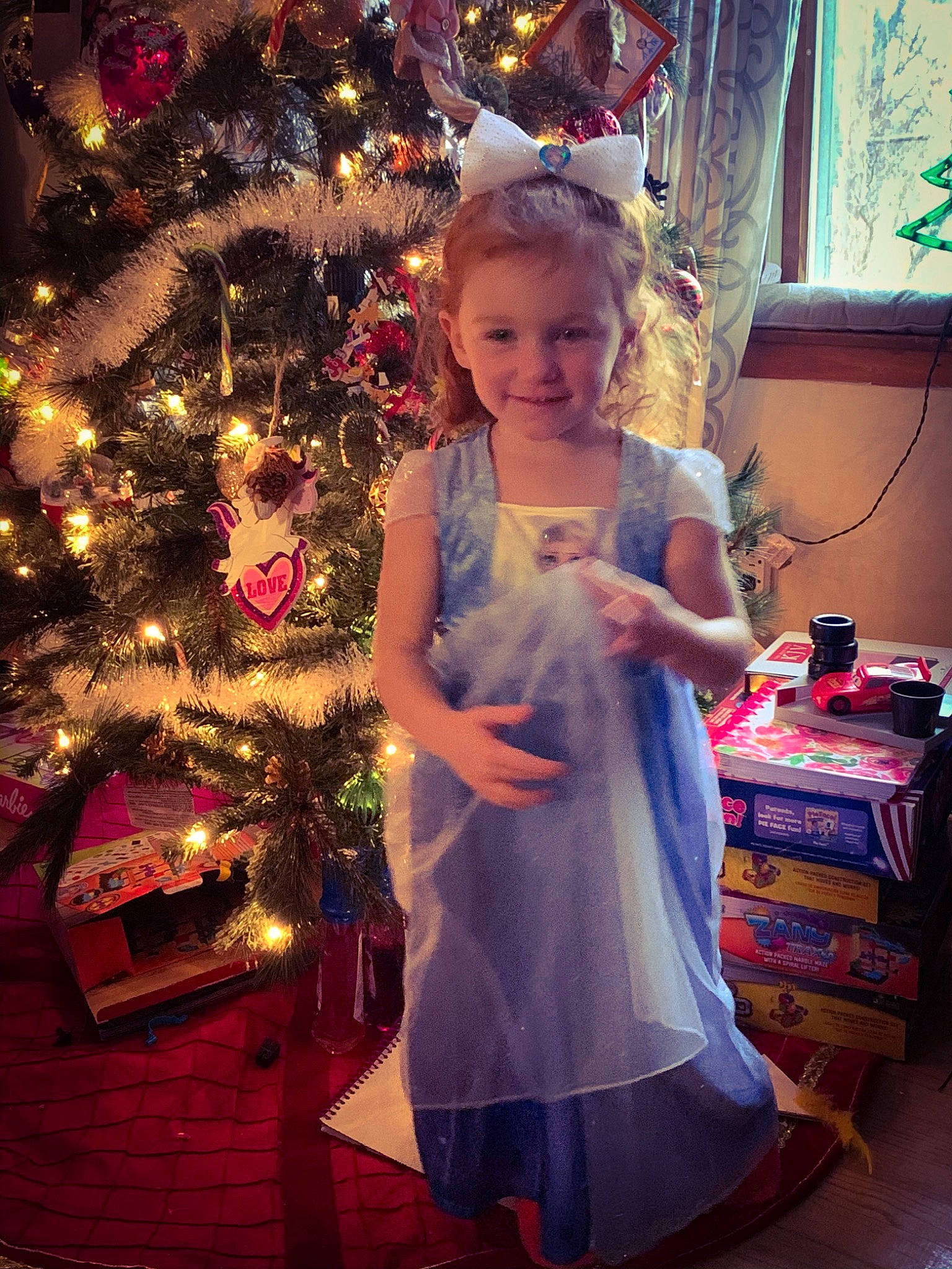 Eleanora is registered to the contest to win money with this photo: box, christmas, christmas_decoration, christmas_eve, christmas_lights, christmas_ornament, christmas_tree, conifer, curtain, day_dress, dress, fictional_character, hair_accessory, holiday, holiday_ornament, interior_design, joy, one_piece_garment, ornament, party_supply