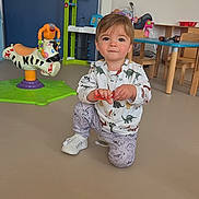 Naël a rejoint le concours — aidez-le/la à gagner de superbes lots ! toddler, child, indoor, playroom, toy, dinosaur_clothing, kneeling, floor, table, chair, plastic_toy, colorful, young_child, person, casual_clothing, cute, play, baby, furniture, smiling