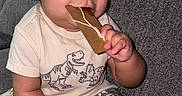 Kenai is registered to the contest to win money with this photo: baby, child, dinosaur, hat, bucket_hat, cookie, gingerbread, couch, clothing, pattern, sitting, cute, happy, indoor, portrait, hand, foot, skin, face, chewing
