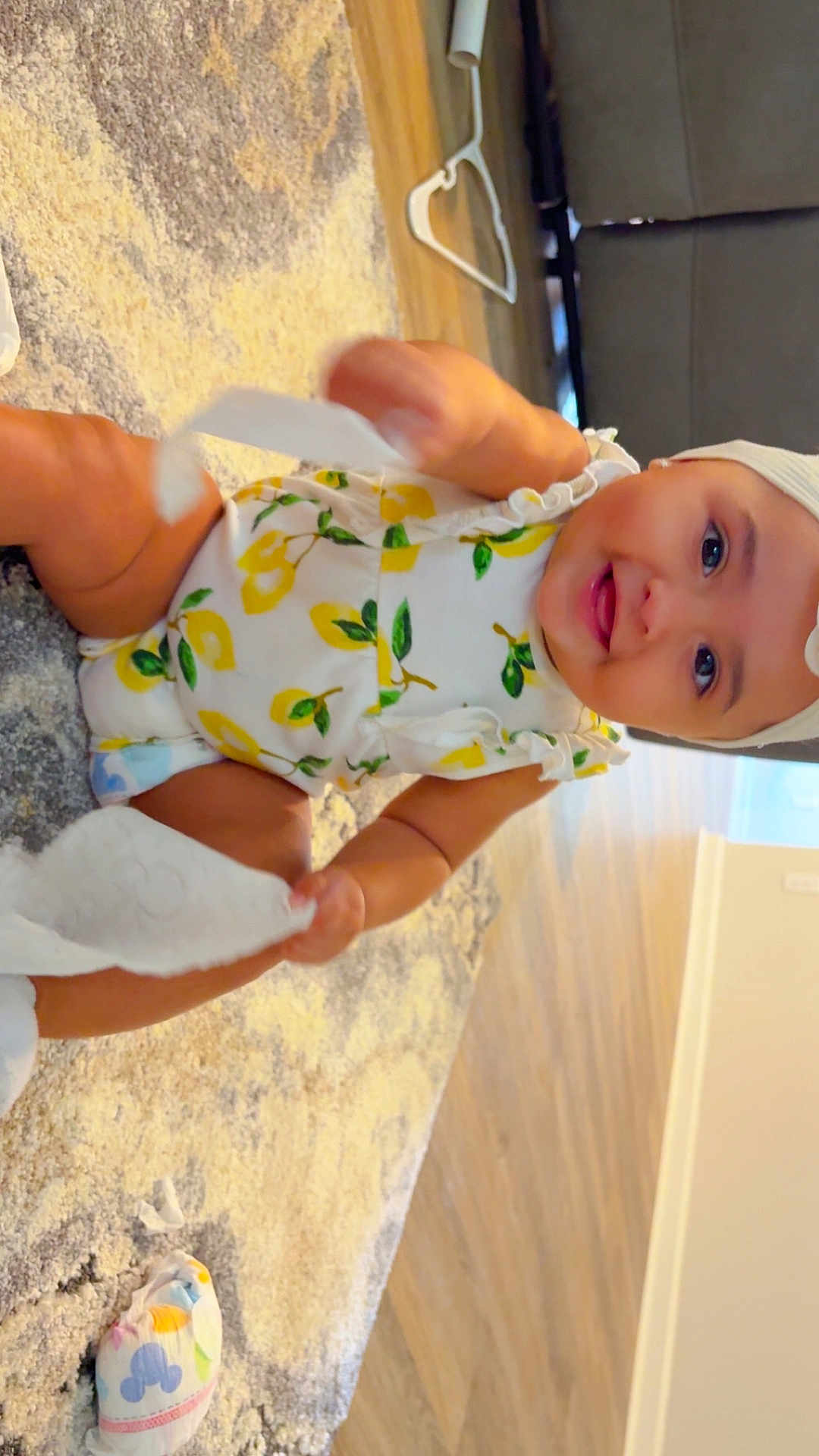 Kiyomi is registered to the contest to win money with this photo: baby, child, smiling, indoor, carpet, floor, tissue_paper, clothing, hat, cute, playing, happy, infant, person, home, furniture, diaper, wooden_floor, patterned_clothing, headwear