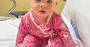 Shyanne is registered to the contest to win money with this photo: baby, infant, pink_clothing, floral_pattern, hospital_bed, medical_equipment, white_bed, child, cute, sitting, indoors, person, young_child, onesie, expression, blue_eyes, head, face, pajamas, hospital_room