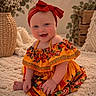 baby, child, infant, portrait, smiling, happy, sitting, red_bow, headband, floral_dress, colorful_clothing, orange_dress, barefoot, indoor, blanket, cozy, basket, houseplant, home_decor, photography