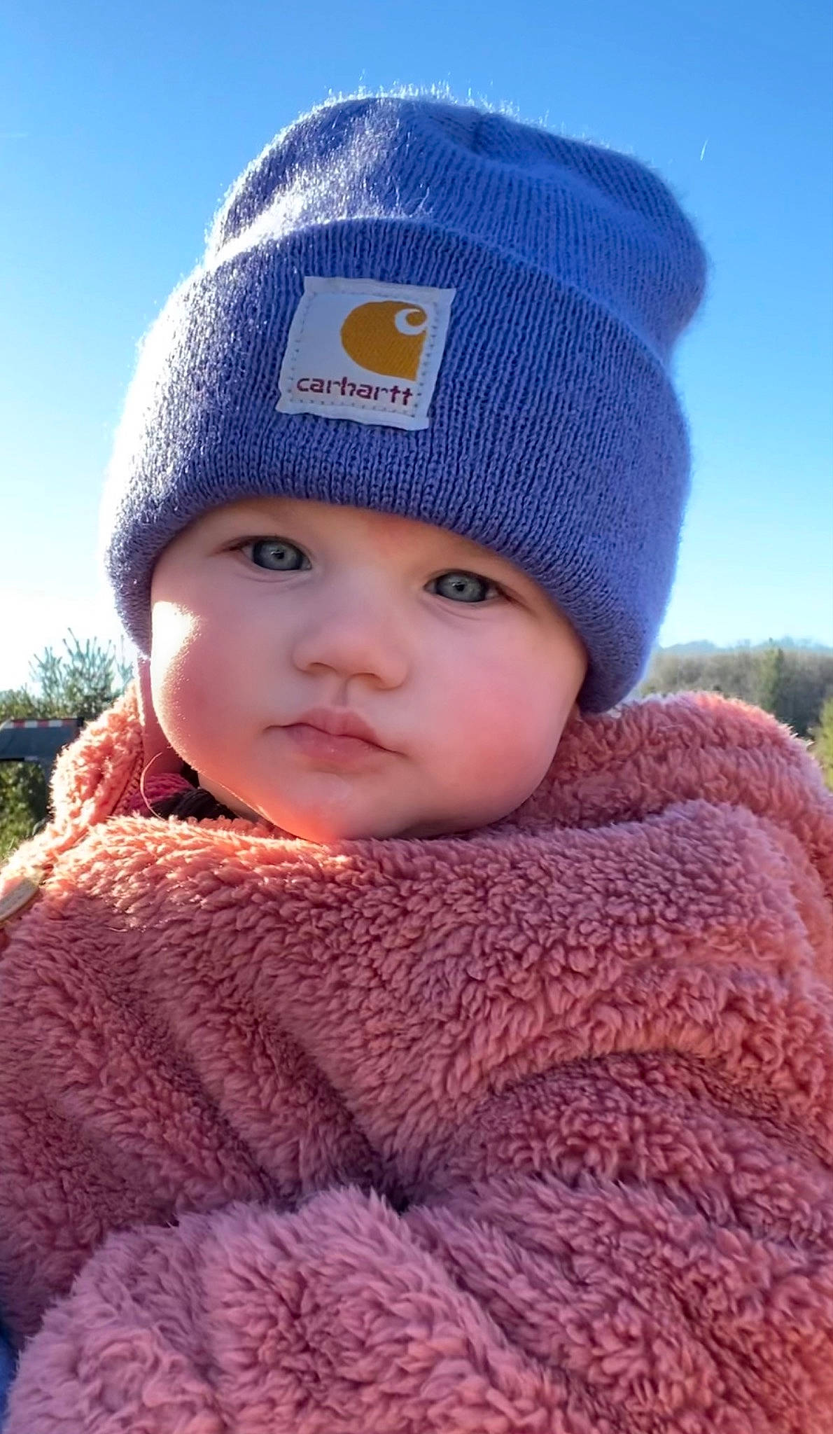 Sadie is registered to the contest to win money with this photo: baby, beanie, cap, cheek, child, electric_blue, face, fashion_accessory, fur, grass, headgear, headwear, knit_cap, pattern, person, portrait_photography, sky, sleeve, toddler, winter