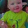 baby, infant, child, portrait, sitting, avocado_shirt, green_clothing, smiling, face, eyes, indoor, home, furniture, chair, table, date_stamp, close_up, casual_photo, baby_diaper, adorable
